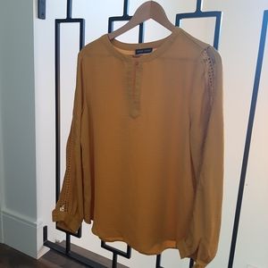 Trendy mustard yellow women's blouse with lace detail.